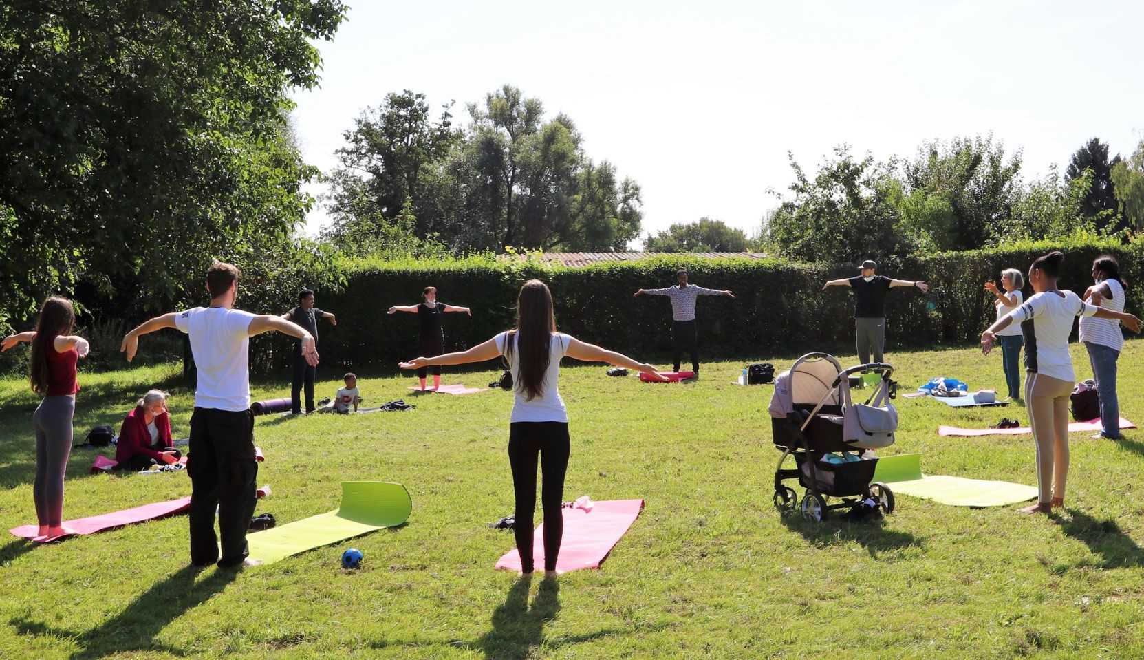 Auf einer Wiese findet ein Yogakurs statt.